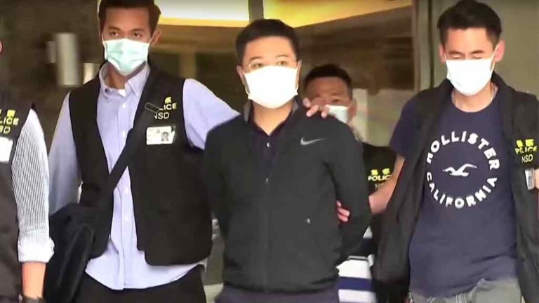 Az Apple Daily Hongkongi lap egyik újságíróját kísérik ki a rendőrök a szerkesztőségi épületből