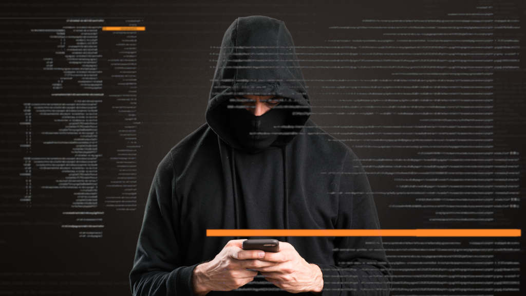 Hacker, a kezében mobiltelefonnal.