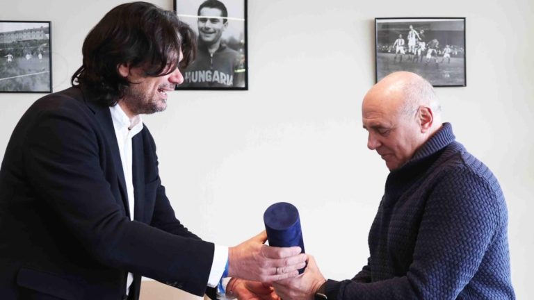 Rónai Egon műsorvezető 2022. december 4-én az MTK Budapest stadionjában átveszi Deutsch Tamás klubelnöktől „az MTK örökös szurkolója” díiszoklevelet. Forrás: az MTK Budapest Facebook oldala.