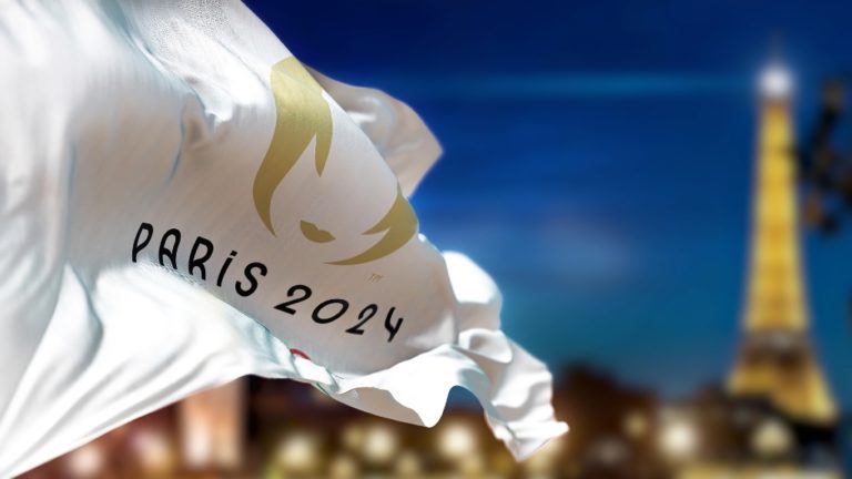 Párizs, Franciaország, 2023. január. A 2024-es párizsi nyári olimpiai játékok zászlaja lobog a szélben; háttérben az Eiffel-torony.
