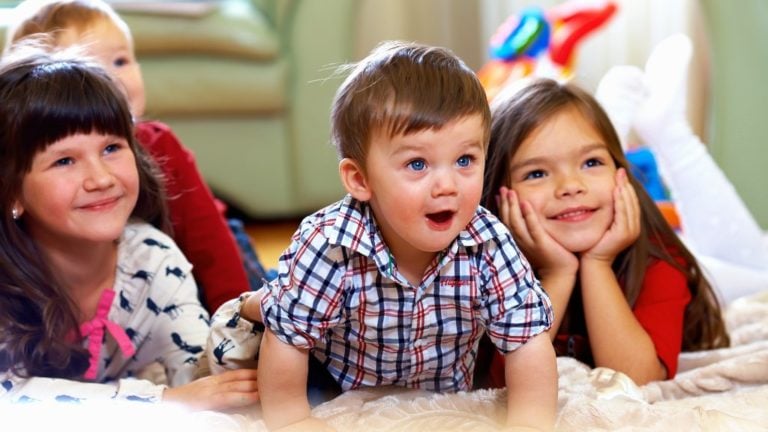 Boldog kisgyerekek csoportja otthon tévét néz.